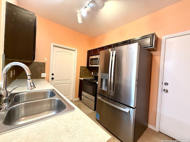 kitchen with track lighting, sink, light tile patterned floors, appliances with stainless steel finishes, and dark brown cabinetry