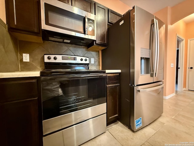 kitchen featuring backsplash, dark brown cabinetry, light tile patterned floors, and stainless steel appliances