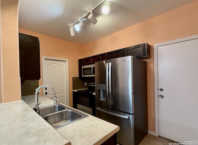 kitchen with rail lighting, dark brown cabinets, sink, and stainless steel appliances