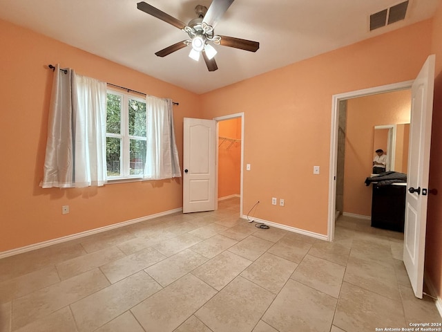 unfurnished bedroom featuring light tile patterned floors, a closet, a spacious closet, and ceiling fan