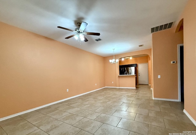 tiled spare room with ceiling fan with notable chandelier