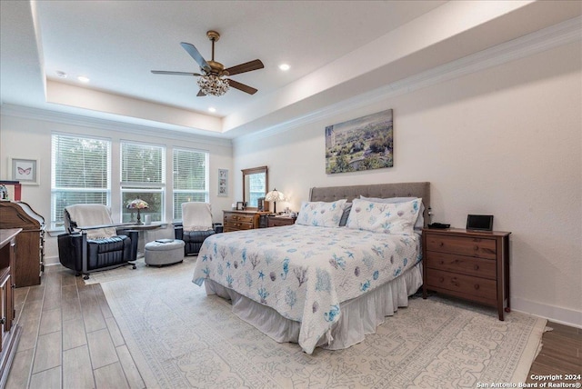 bedroom featuring a raised ceiling, ceiling fan, crown molding, and light hardwood / wood-style floors