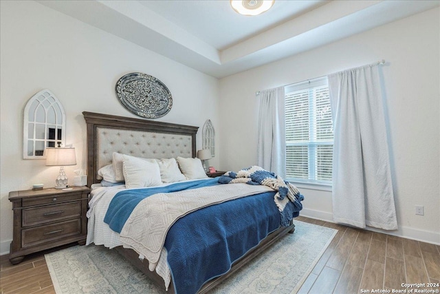 bedroom featuring a tray ceiling and light wood-type flooring