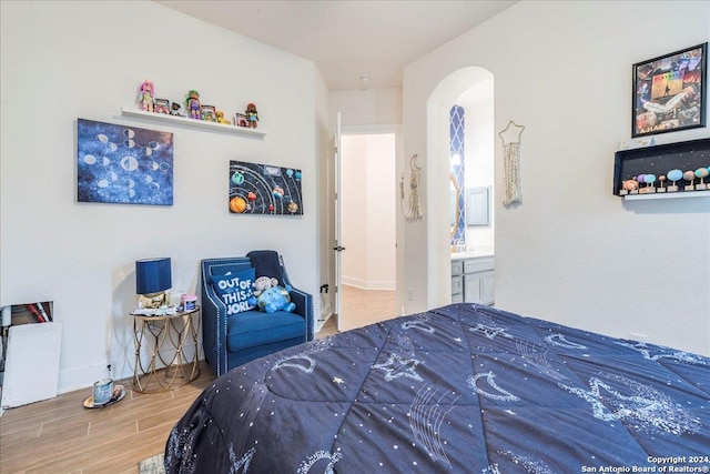 bedroom with wood-type flooring and connected bathroom