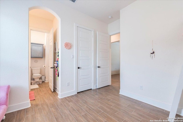 unfurnished bedroom featuring light wood-type flooring and ensuite bath