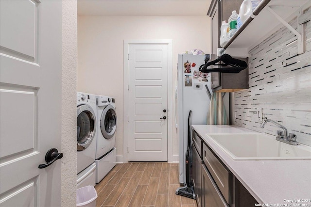 laundry area featuring washing machine and dryer, sink, and light hardwood / wood-style floors