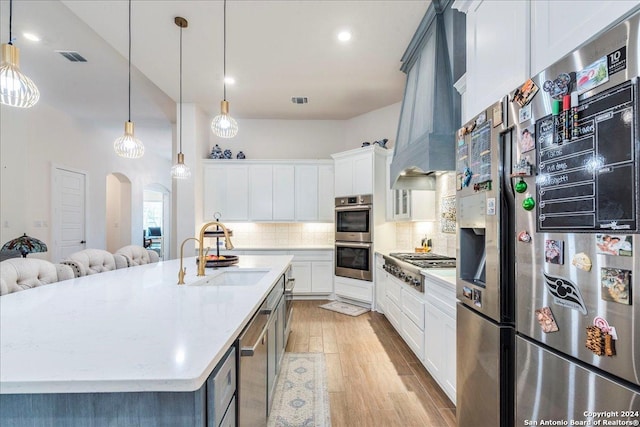 kitchen with white cabinets, sink, light wood-type flooring, a large island, and stainless steel appliances