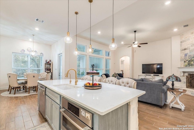 kitchen featuring decorative light fixtures, a wealth of natural light, sink, and a kitchen island with sink