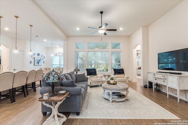 living room with ceiling fan with notable chandelier and hardwood / wood-style flooring