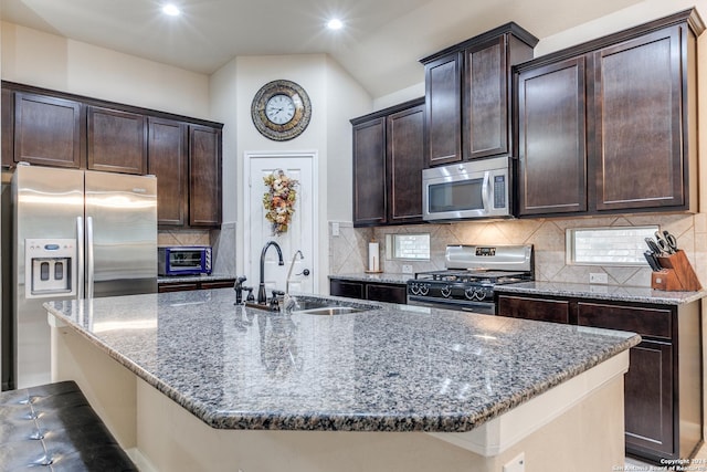 kitchen featuring tasteful backsplash, sink, appliances with stainless steel finishes, and an island with sink