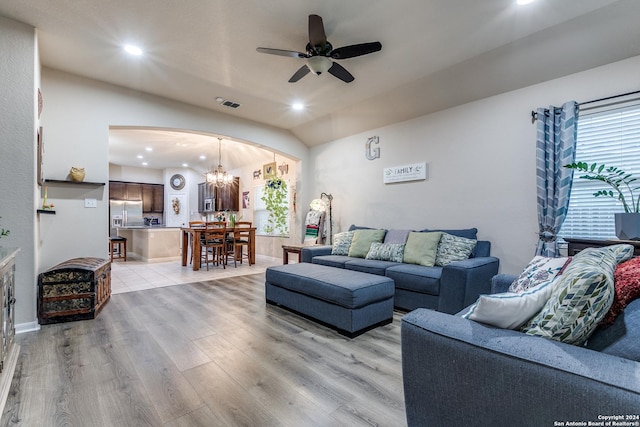 living room featuring ceiling fan with notable chandelier, light wood-type flooring, and lofted ceiling