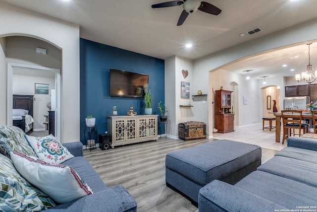 living room featuring light hardwood / wood-style floors and ceiling fan with notable chandelier