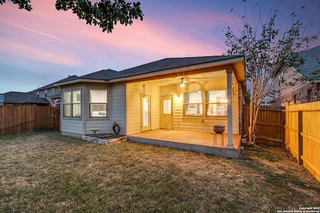 back house at dusk with a patio area and a yard