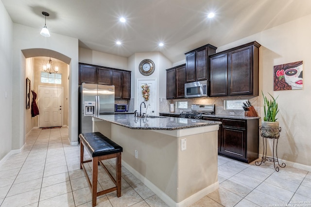 kitchen featuring a kitchen bar, appliances with stainless steel finishes, tasteful backsplash, sink, and an island with sink