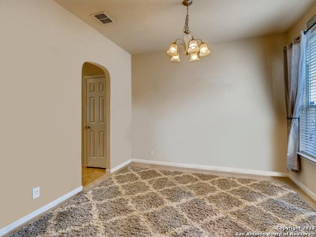 carpeted spare room with a chandelier