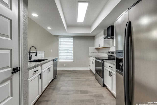 kitchen with white cabinets, appliances with stainless steel finishes, light stone counters, and sink