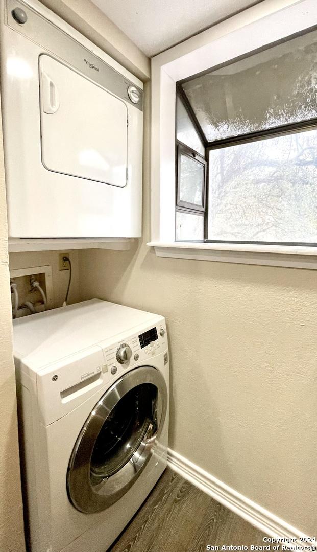 washroom featuring dark hardwood / wood-style flooring, a wealth of natural light, and stacked washer and clothes dryer