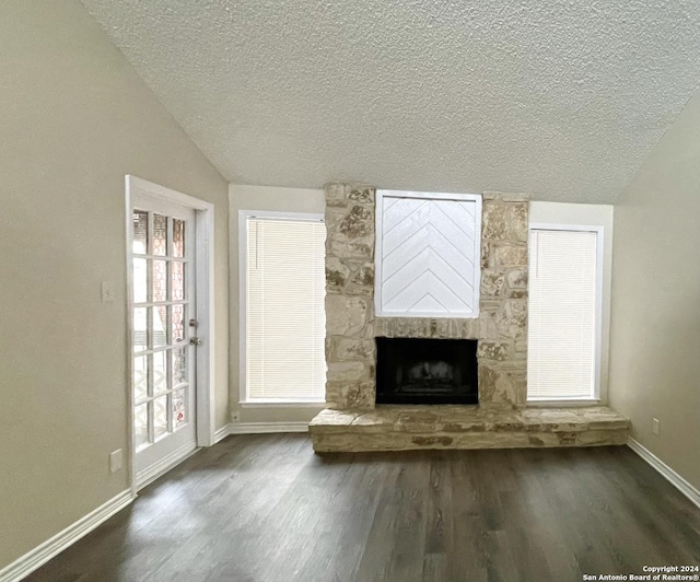 unfurnished living room with a fireplace, dark hardwood / wood-style flooring, a textured ceiling, and vaulted ceiling