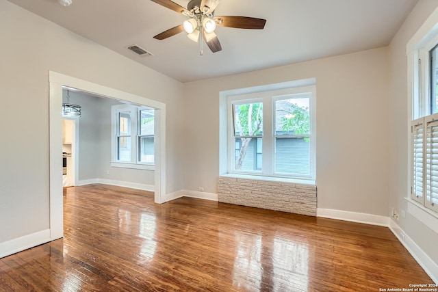 unfurnished room featuring hardwood / wood-style floors, ceiling fan with notable chandelier, and plenty of natural light