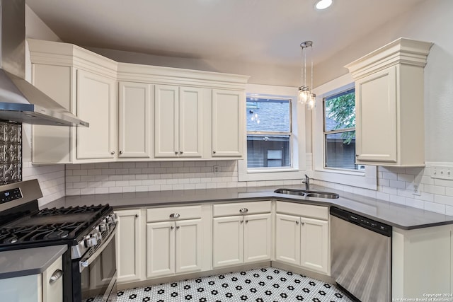 kitchen with sink, wall chimney exhaust hood, pendant lighting, decorative backsplash, and appliances with stainless steel finishes