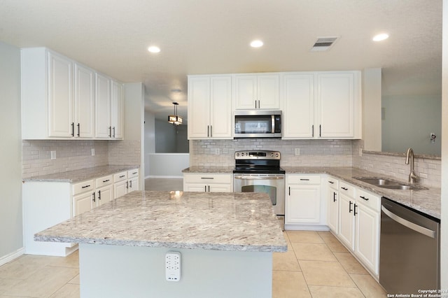 kitchen featuring white cabinets, sink, light stone countertops, and stainless steel appliances