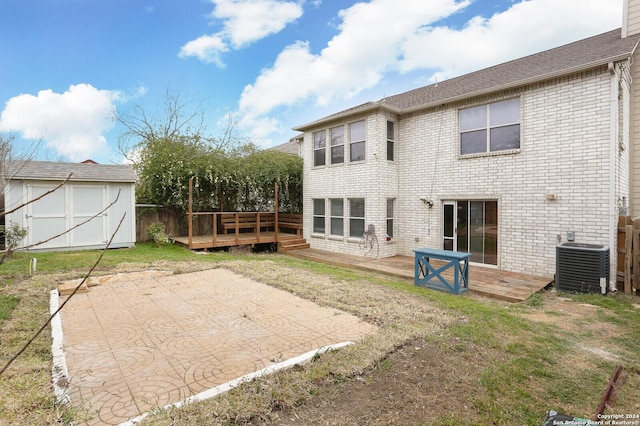 rear view of house featuring cooling unit, a shed, a yard, a patio area, and a deck