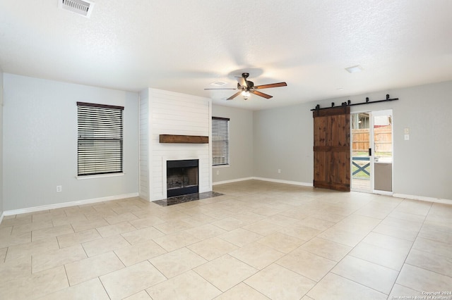 unfurnished living room with a textured ceiling, ceiling fan, light tile patterned floors, and a fireplace