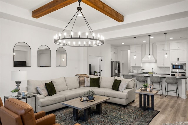 living room featuring light hardwood / wood-style flooring, beamed ceiling, and a chandelier