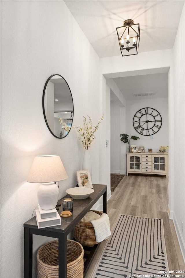 hallway with hardwood / wood-style floors and a chandelier