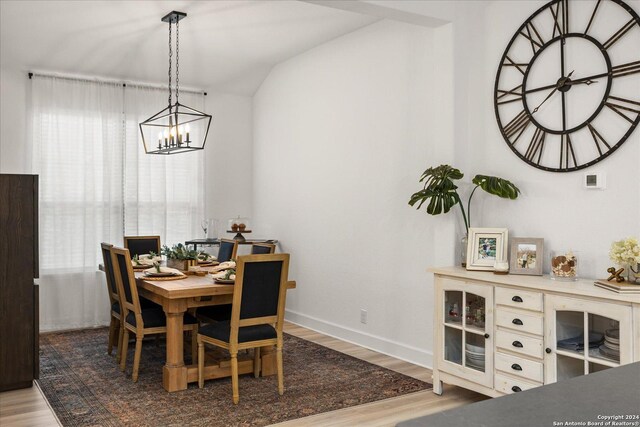 dining room featuring a chandelier, wood-type flooring, and vaulted ceiling