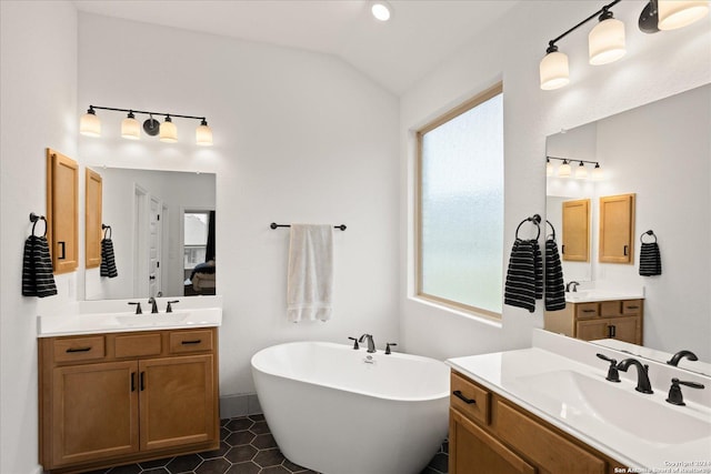 bathroom featuring tile patterned flooring, vanity, a tub to relax in, and vaulted ceiling