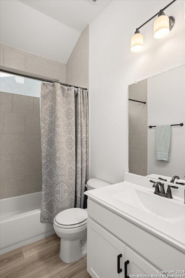 full bathroom with hardwood / wood-style floors, vanity, lofted ceiling, toilet, and shower / tub combo