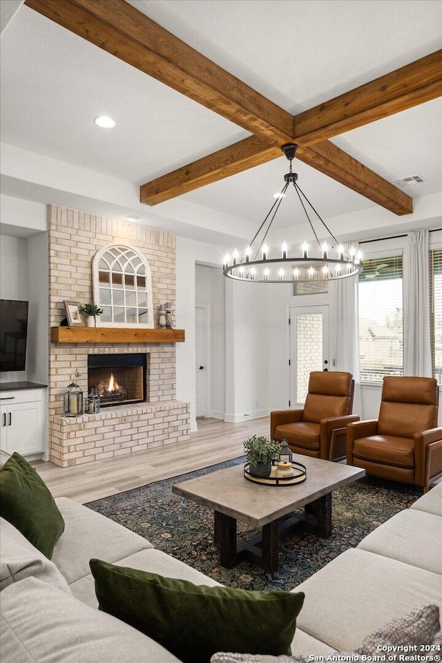 living room with beam ceiling, hardwood / wood-style floors, and a brick fireplace