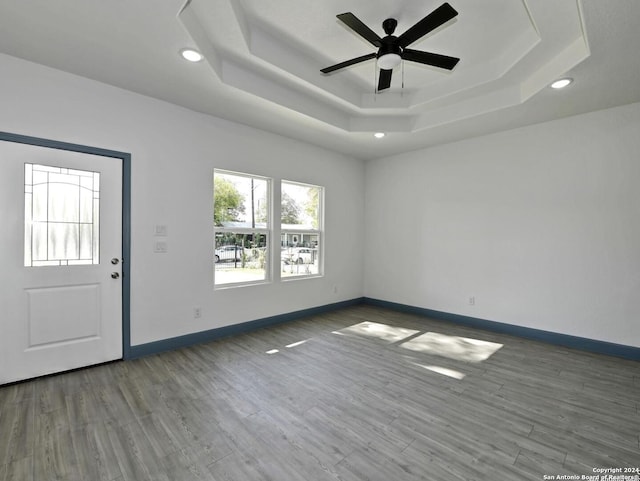 interior space featuring wood-type flooring, a raised ceiling, and ceiling fan