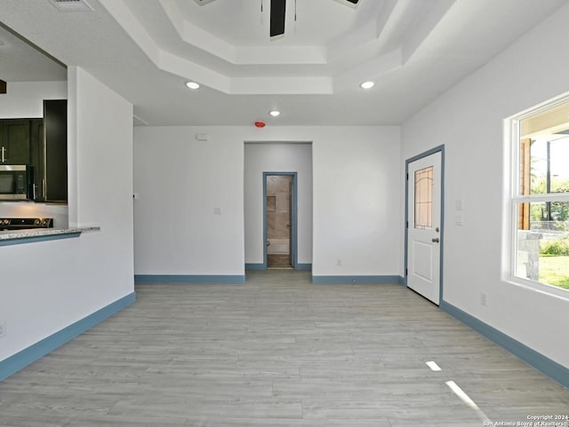 unfurnished room featuring a tray ceiling, light hardwood / wood-style flooring, and ceiling fan