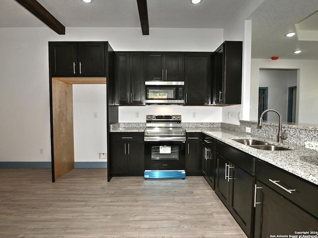 kitchen with beam ceiling, sink, light hardwood / wood-style floors, and appliances with stainless steel finishes