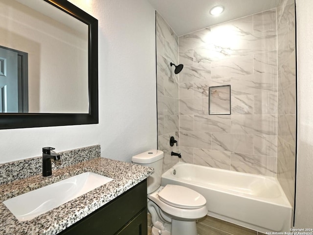 full bathroom featuring vanity, tiled shower / bath combo, and toilet