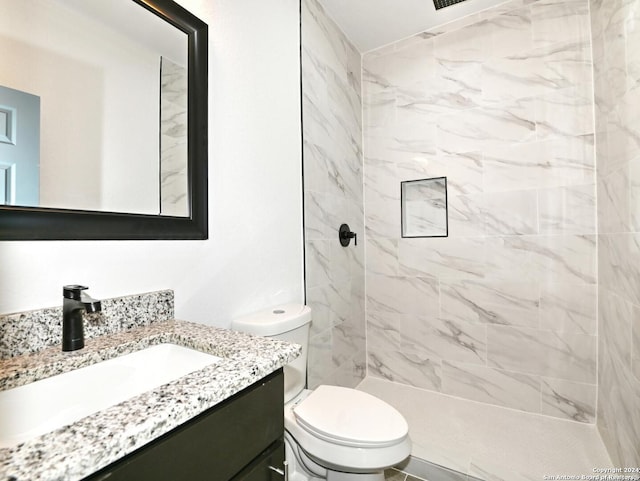 bathroom featuring vanity, toilet, and a tile shower