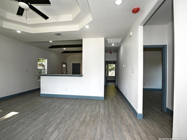 unfurnished living room with dark hardwood / wood-style floors, ceiling fan, a textured ceiling, and a tray ceiling