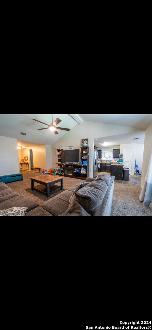 living room featuring carpet floors, ceiling fan, and lofted ceiling