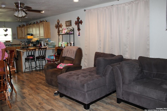 living room featuring ceiling fan, dark hardwood / wood-style floors, and a textured ceiling