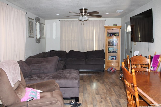 living room featuring dark hardwood / wood-style flooring, a textured ceiling, and ceiling fan