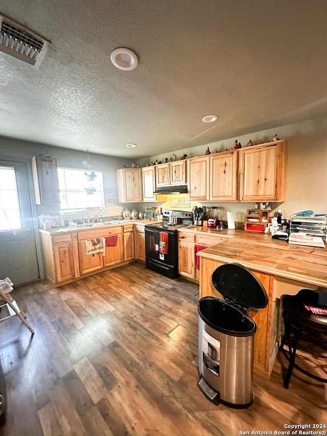 kitchen with a textured ceiling, black range with electric cooktop, light hardwood / wood-style flooring, butcher block countertops, and hanging light fixtures