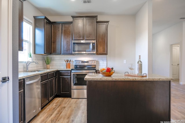 kitchen with a kitchen island, sink, appliances with stainless steel finishes, and light hardwood / wood-style flooring