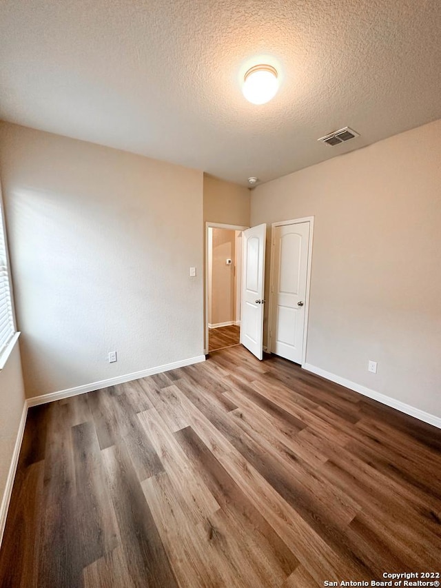 unfurnished bedroom with a textured ceiling and hardwood / wood-style flooring