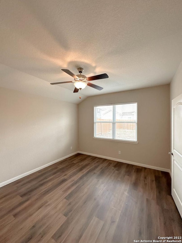 spare room featuring a textured ceiling, dark hardwood / wood-style flooring, vaulted ceiling, and ceiling fan