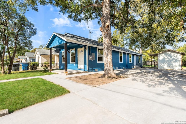 view of front of house with a carport, covered porch, an outdoor structure, and a front yard