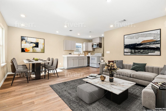 living room with light hardwood / wood-style floors and sink