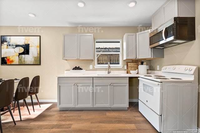 kitchen with white electric range oven, light wood-type flooring, and sink