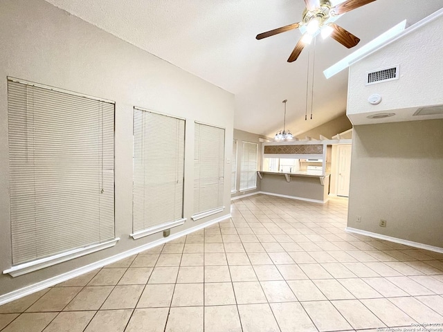 interior space with ceiling fan with notable chandelier, light tile patterned floors, and high vaulted ceiling